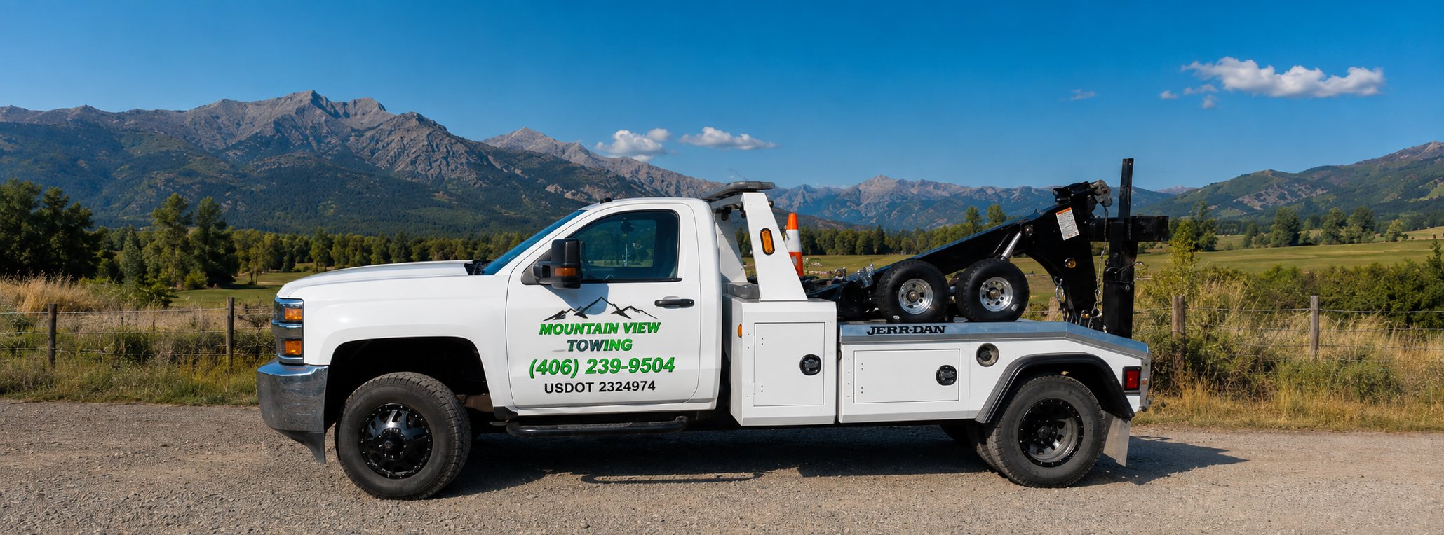 Mountain View Towing flatbed tow truck parked with Montana mountain range in the background near Deer Lodge